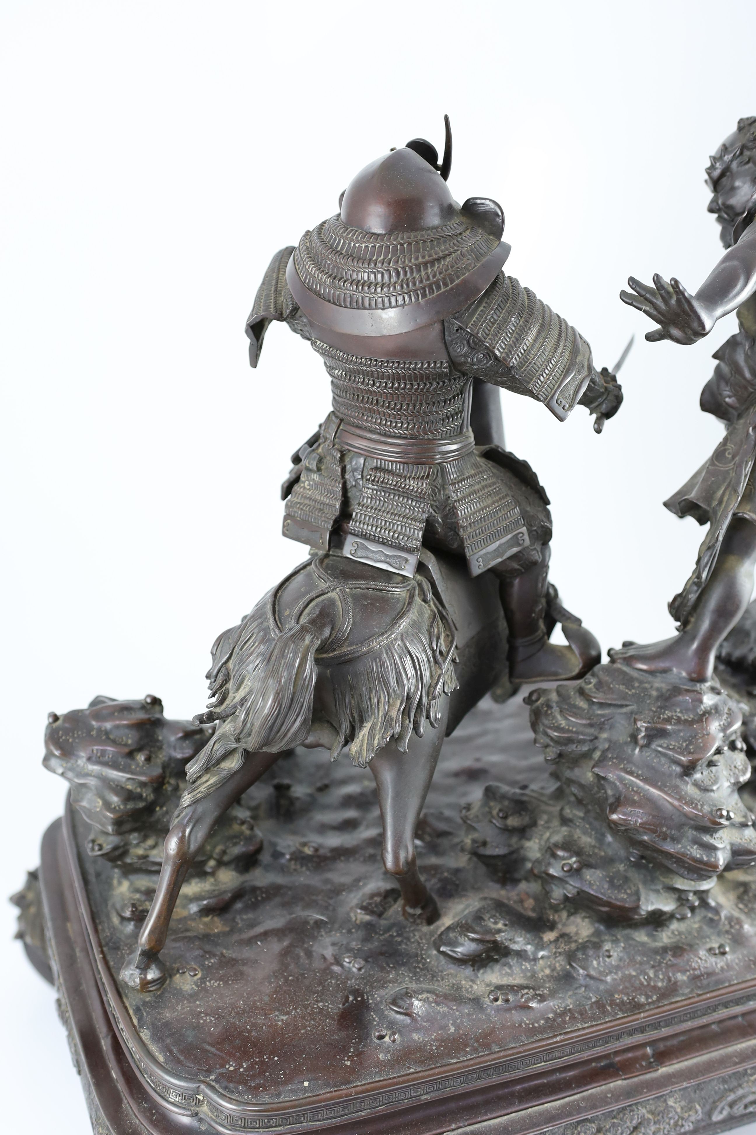 An impressive Japanese bronze group of an oni attacking a Samurai on horseback, Meiji period, 58cm high 49.5cm wide